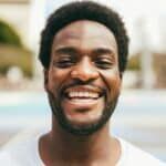 Happy African man smiling at camera inside basketball court - Focus on mouth