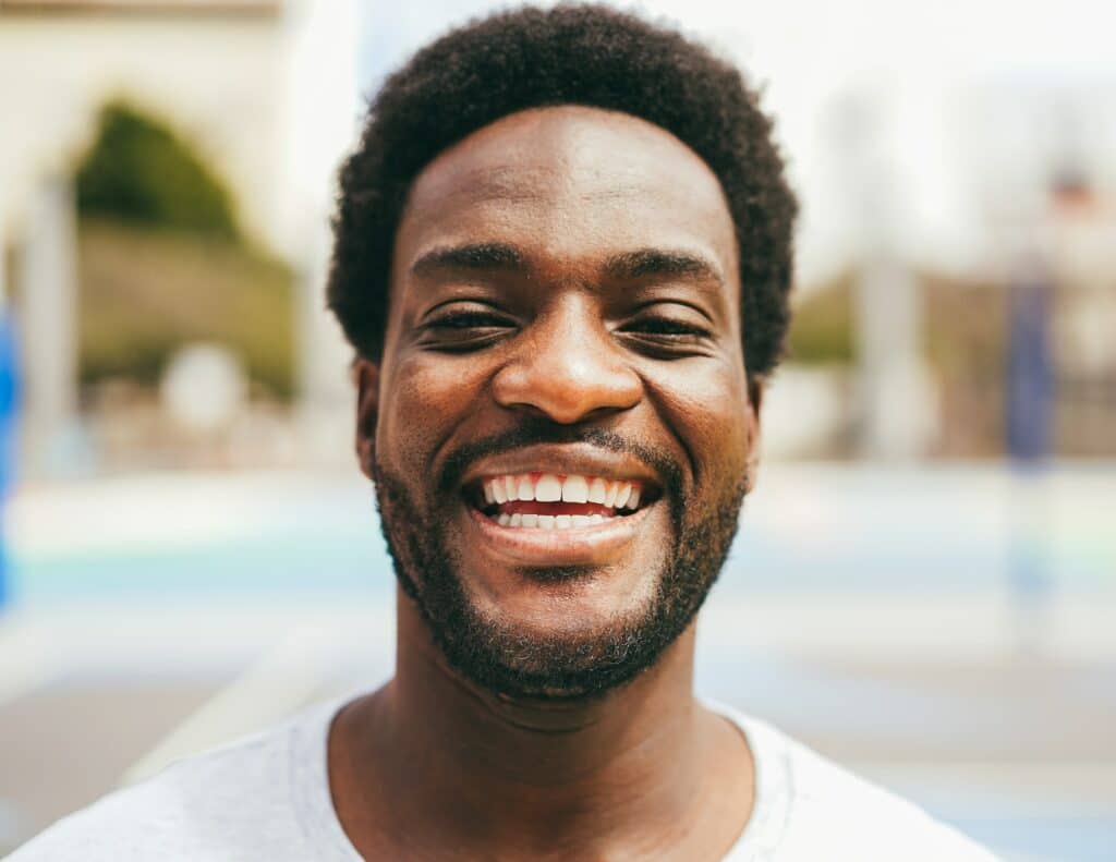 Happy African man smiling at camera inside basketball court - Focus on mouth