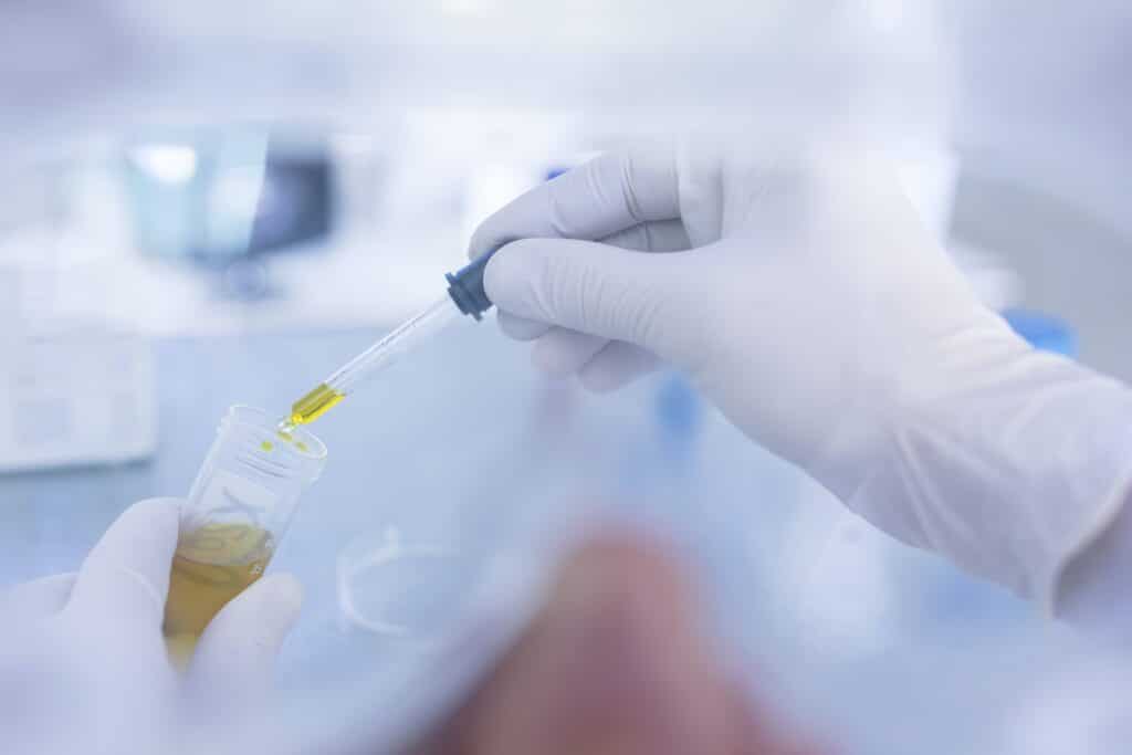 Laboratory worker taking liquid from test tube, using pipette, close-up