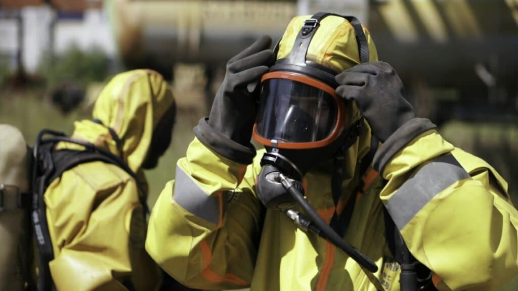 Man adjusting a gas mask. Clip. An employee who is wearing a gas mask and a yellow suit is an